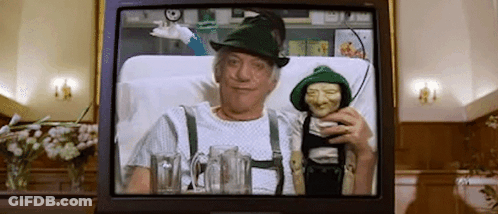 A Man In A Green Hat Is Sitting In A Hospital Bed Holding A Puppet . GIF