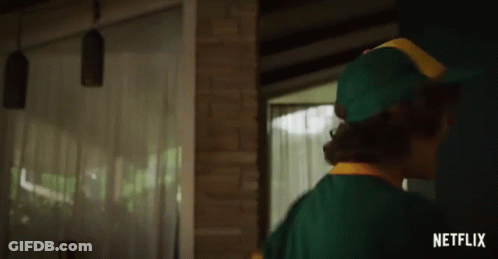 A Man In A Green Hat Is Standing In Front Of A Brick Wall With A Netflix Logo Behind Him GIF