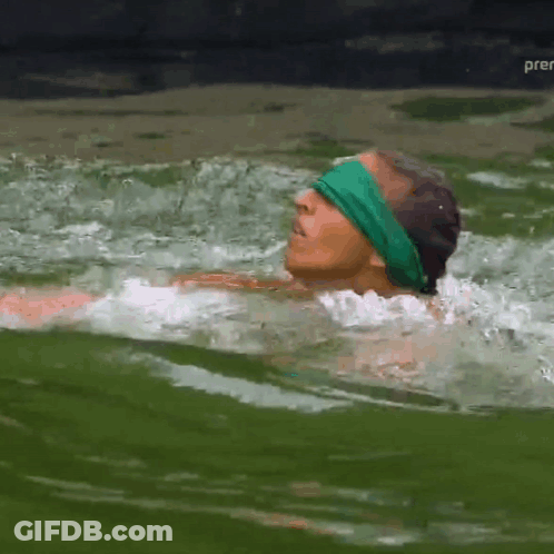 A Man In A Green Headband Is Swimming In A Body Of Water GIF