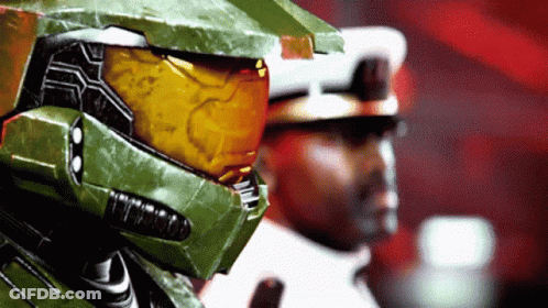 A Man In A Green Helmet Stands Next To Another Man In A White Uniform GIF