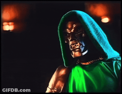 A Man In A Green Hooded Cape Holds A Fist In The Air GIF