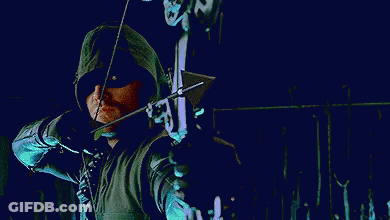 A Man In A Green Hooded Jacket Is Holding A Bow And Arrow In His Hand . GIF