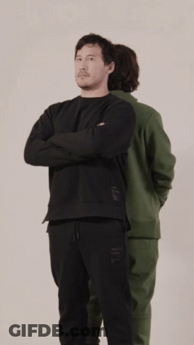 A Man In A Green Hoodie And A Man In A Black Hoodie Are Standing Back To Back GIF