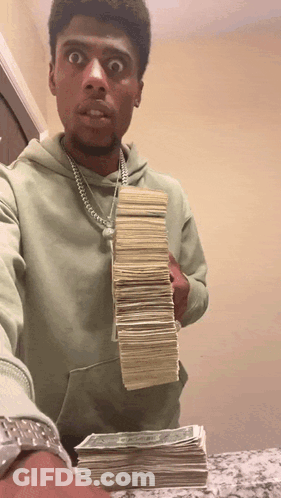 A Man In A Green Hoodie Holds Up A Stack Of Money GIF
