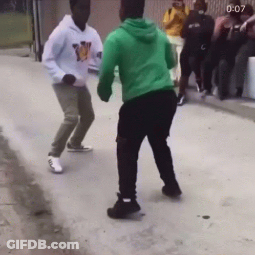 A Man In A Green Hoodie Is Dancing With Another Man GIF