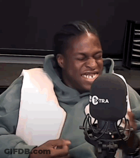 A Man In A Green Hoodie Is Sitting In Front Of A Microphone . GIF