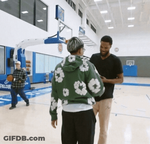 A Man In A Green Hoodie Is Talking To Another Man GIF