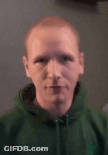 A Man In A Green Hoodie Looks At The Camera . GIF
