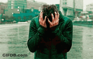 A Man In A Green Jacket Is Covering His Face With His Hands . GIF