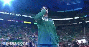 A Man In A Green Jacket Is Singing Into A Microphone In Front Of A Banner That Says Tonight 'S Sponsor GIF