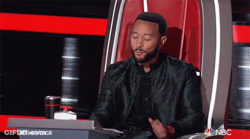 A Man In A Green Jacket Is Sitting In A Chair With A Nbc Logo In The Background GIF
