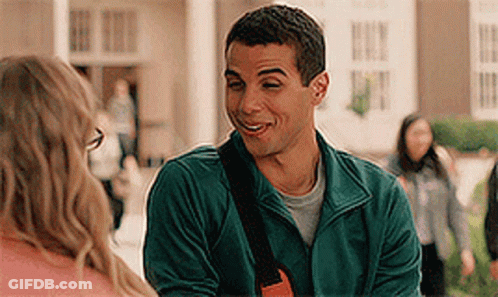 A Man In A Green Jacket Is Smiling And Talking To A Woman . GIF