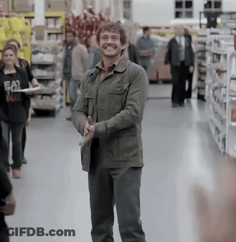 A Man In A Green Jacket Is Smiling In A Grocery Store While Holding A Knife GIF