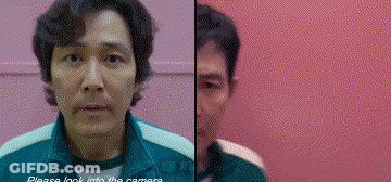 A Man In A Green Jacket Is Standing In Front Of A Pink Wall And Looking At The Camera . GIF