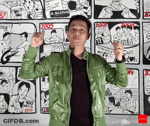 Man In Green Jacket In Front Of Comic Wall GIF