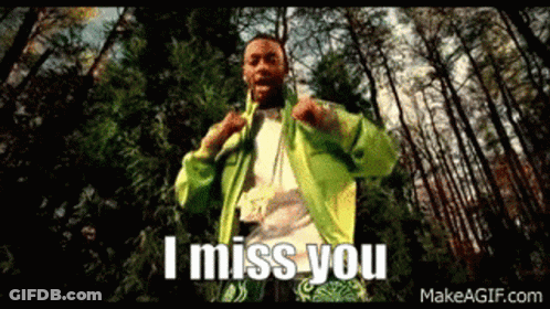 A Man In A Green Jacket Is Standing In The Woods With The Words `` I Miss You '' Written On The Screen . GIF