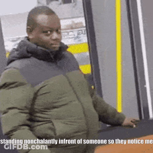 A Man In A Green Jacket Is Standing Nonchalantly In Front Of Someone So They Notice Me GIF
