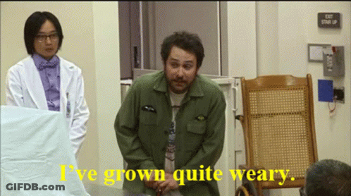 A Man In A Green Jacket Says " I 'Ve Grown Quite Weary " In Front Of An Exit Sign GIF