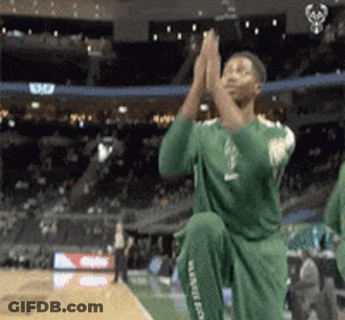 A Man In A Green Jersey Is Kneeling Down And Clapping GIF