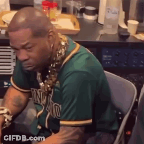 A Man In A Green Jersey Is Sitting In A Chair In Front Of A Piano . GIF