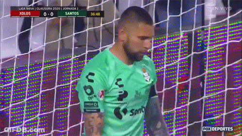 A Man In A Green Santos Jersey Is Standing In Front Of A Soccer Net GIF