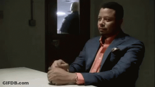 A Man In A Green Scrub Suit Is Sitting At A Table With Another Man . GIF