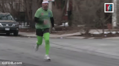 A Man In A Green Shirt And Green Pants Is Running Down A Street GIF
