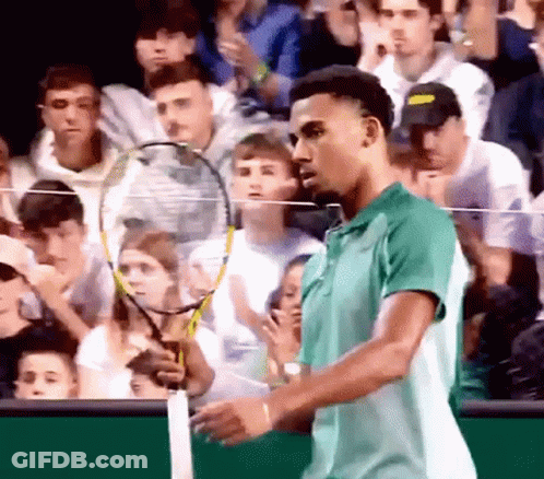 A Man In A Green Shirt Holds A Tennis Racket In Front Of A Crowd GIF