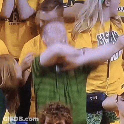 A Man In A Green Shirt Is Being Hugged By A Woman In A Yellow Shirt That Says Ucsd GIF