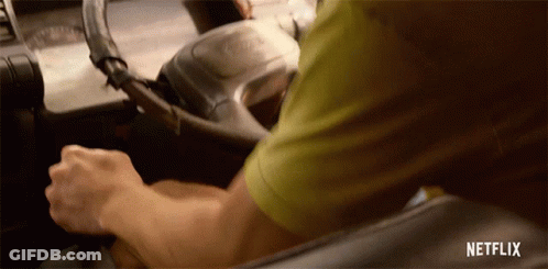 A Man In A Green Shirt Is Driving A Car With Netflix Written On The Bottom Of The Screen GIF