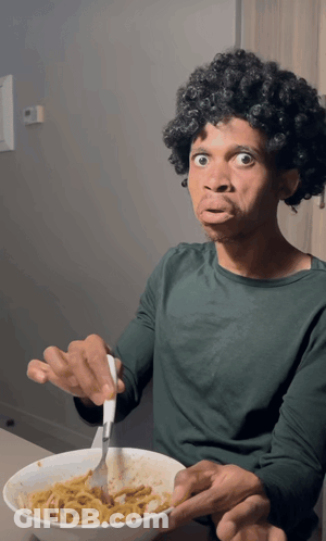A Man In A Green Shirt Is Eating Spaghetti With A Fork GIF