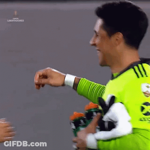 A Man In A Green Shirt Is Giving A Fist Bump To Another Man GIF