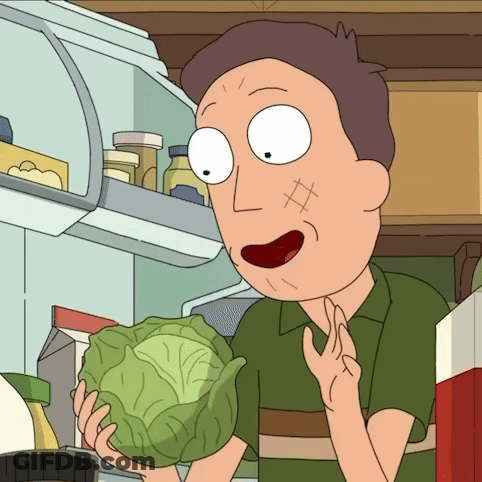 A Man In A Green Shirt Is Holding A Cabbage In Front Of A Refrigerator GIF