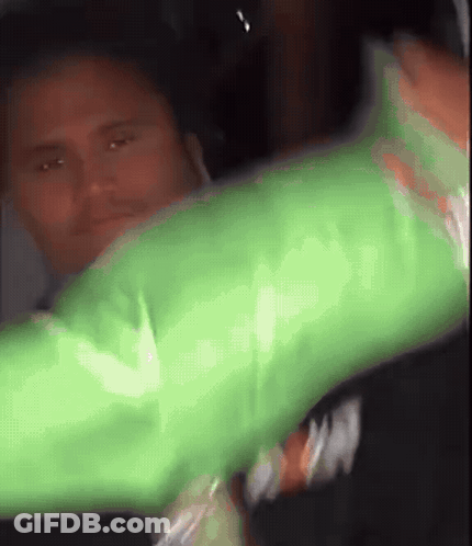 A Man In A Green Shirt Is Holding A Green Object GIF