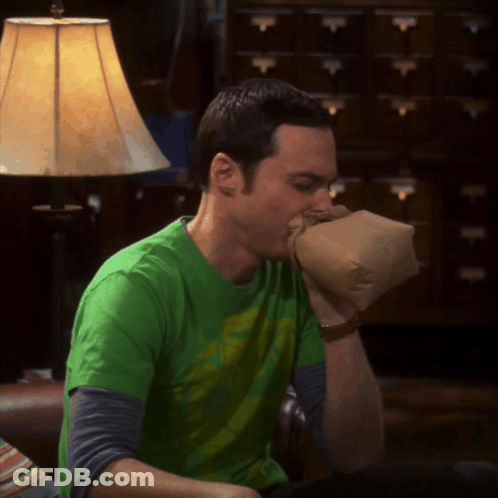 A Man In A Green Shirt Is Holding A Paper Bag In His Mouth GIF