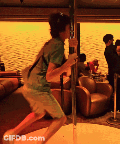 A Man In A Green Shirt Is Holding A Pole In A Room GIF