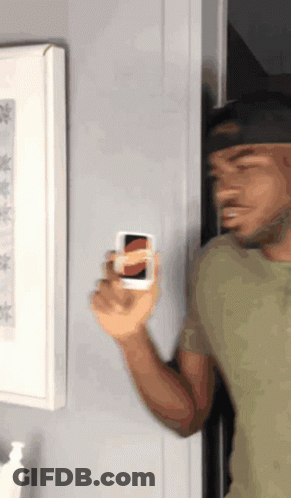 A Man In A Green Shirt Is Holding A Small White Object GIF