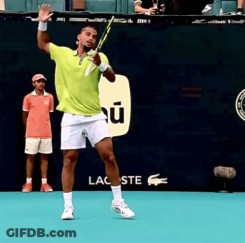 A Man In A Green Shirt Is Holding A Tennis Racquet In Front Of A Lacoste Sign GIF