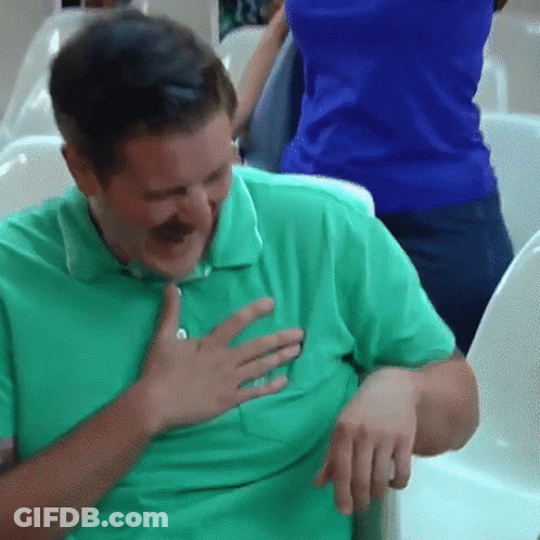 A Man In A Green Shirt Is Holding His Chest And Smiling GIF
