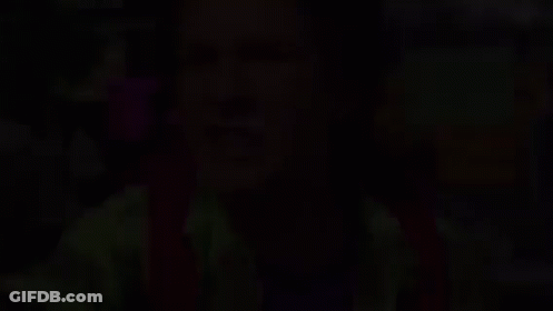 A Man In A Green Shirt Is Making A Funny Face . GIF