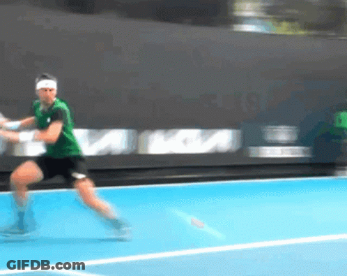 A Man In A Green Shirt Is Playing Tennis On A Court GIF