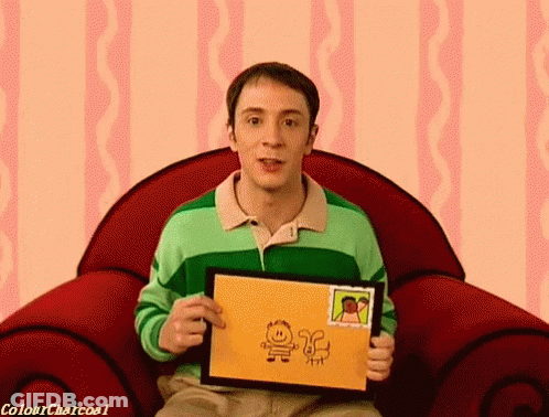 A Man In A Green Shirt Is Sitting In A Red Chair Holding A Drawing GIF
