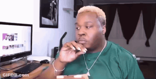 A Man In A Green Shirt Is Sitting In Front Of A Computer Monitor GIF