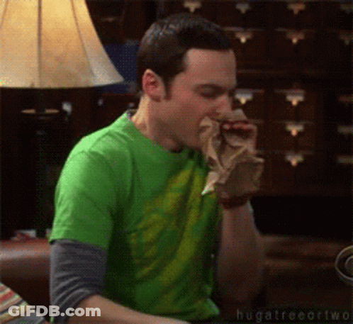 A Man In A Green Shirt Is Sitting On A Couch Eating Something GIF