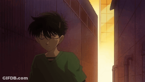 A Man In A Green Shirt Is Standing In A Dark Alleyway GIF