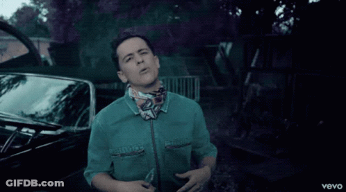 A Man In A Green Shirt Is Standing In Front Of A Black Car With The Word Vevo On The Bottom GIF