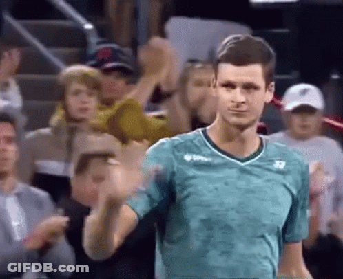 A Man In A Green Shirt Is Standing In Front Of A Crowd . GIF