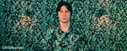 A Man In A Green Shirt Is Standing In Front Of A Wall GIF