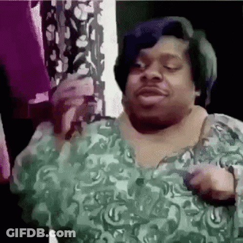 A Man In A Green Shirt Is Standing In Front Of A Window . GIF