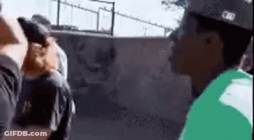 A Man In A Green Shirt Is Standing Next To A Man In A Black Shirt . GIF